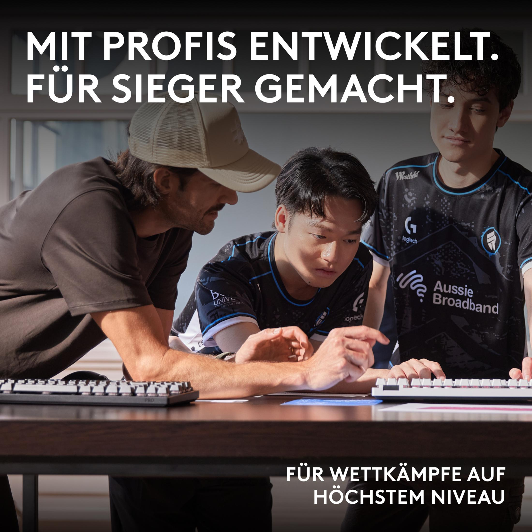 Trzech mężczyzn w koszulkach e-sportowych patrzy na ekran komputera.