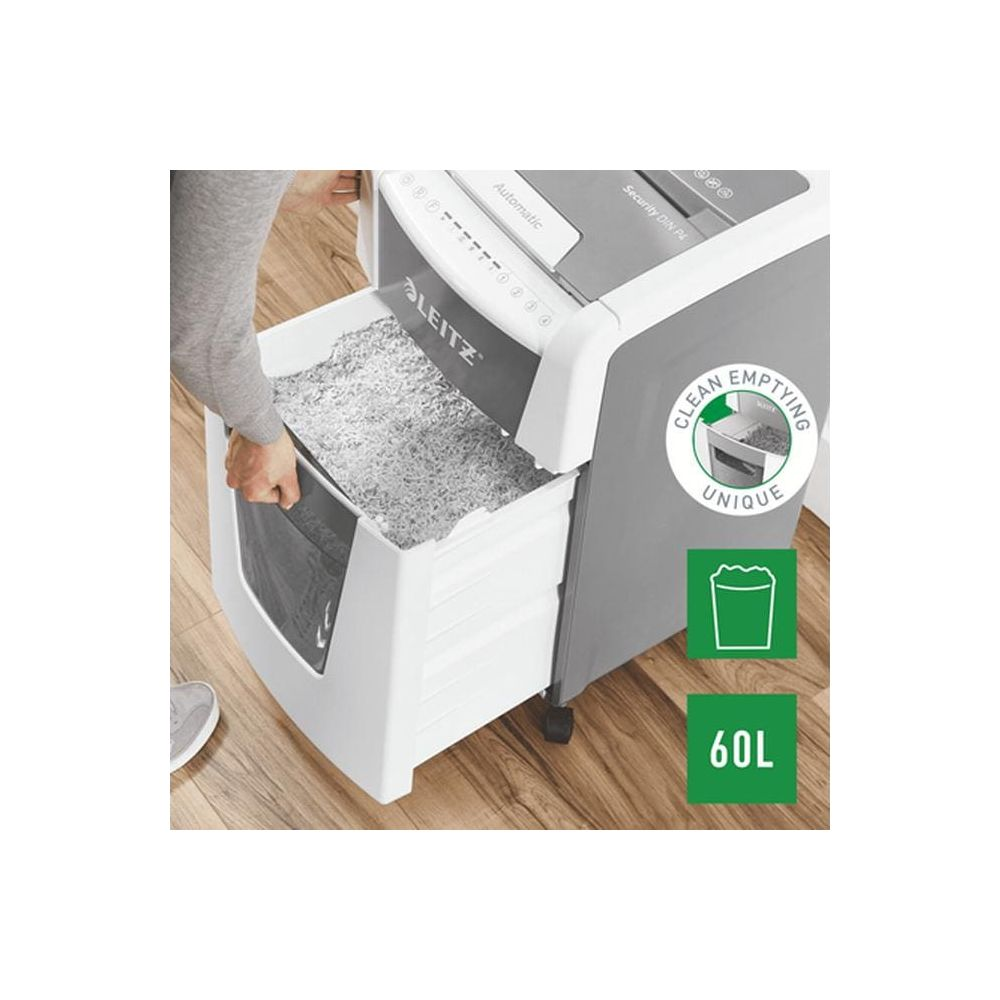 Une personne retire une poubelle pleine de papier déchiqueté d'une déchiqueteuse.