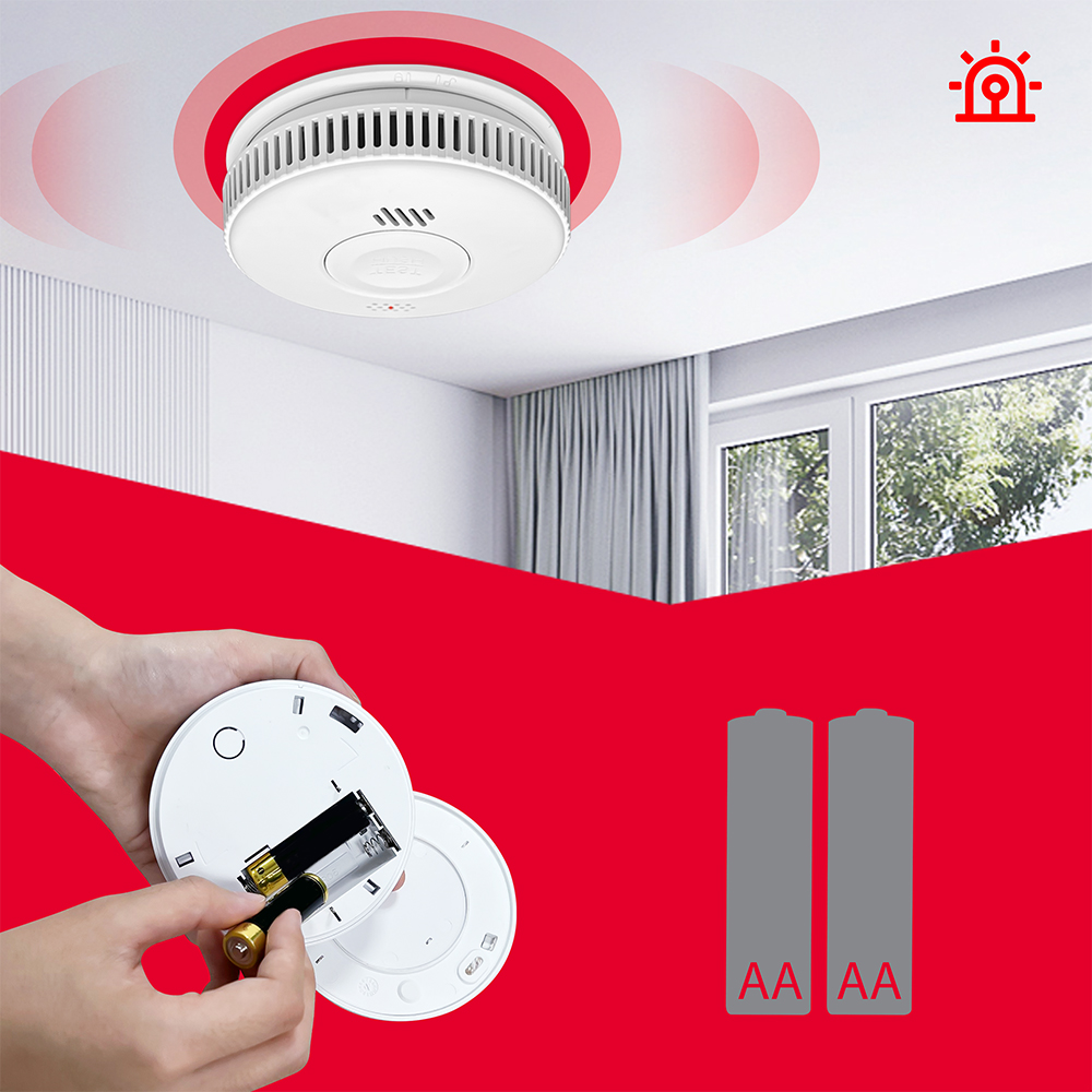 Czujnik dymu na suficie, ręce wkładają baterie. Przedstawiono dwie baterie AA.