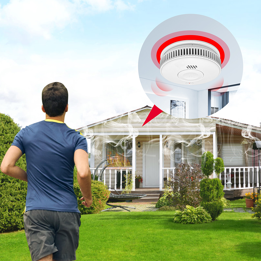 Mężczyzna biegnie po trawniku przed domem z dymem; pokazano czujnik dymu.