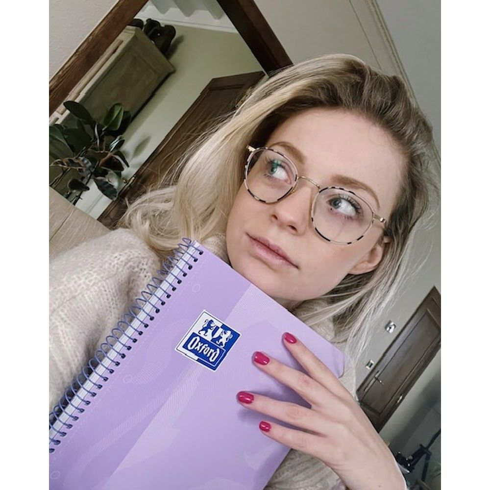Eine Frau mit Brille hält ein lila Notizbuch.