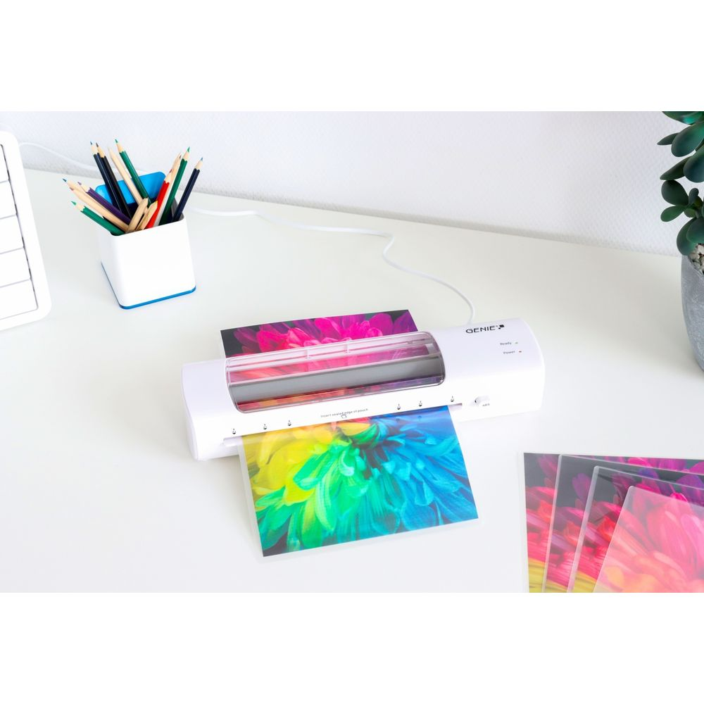 Ein weißer Laminator auf einem Schreibtisch mit farbenfrohen Blumenbildern.