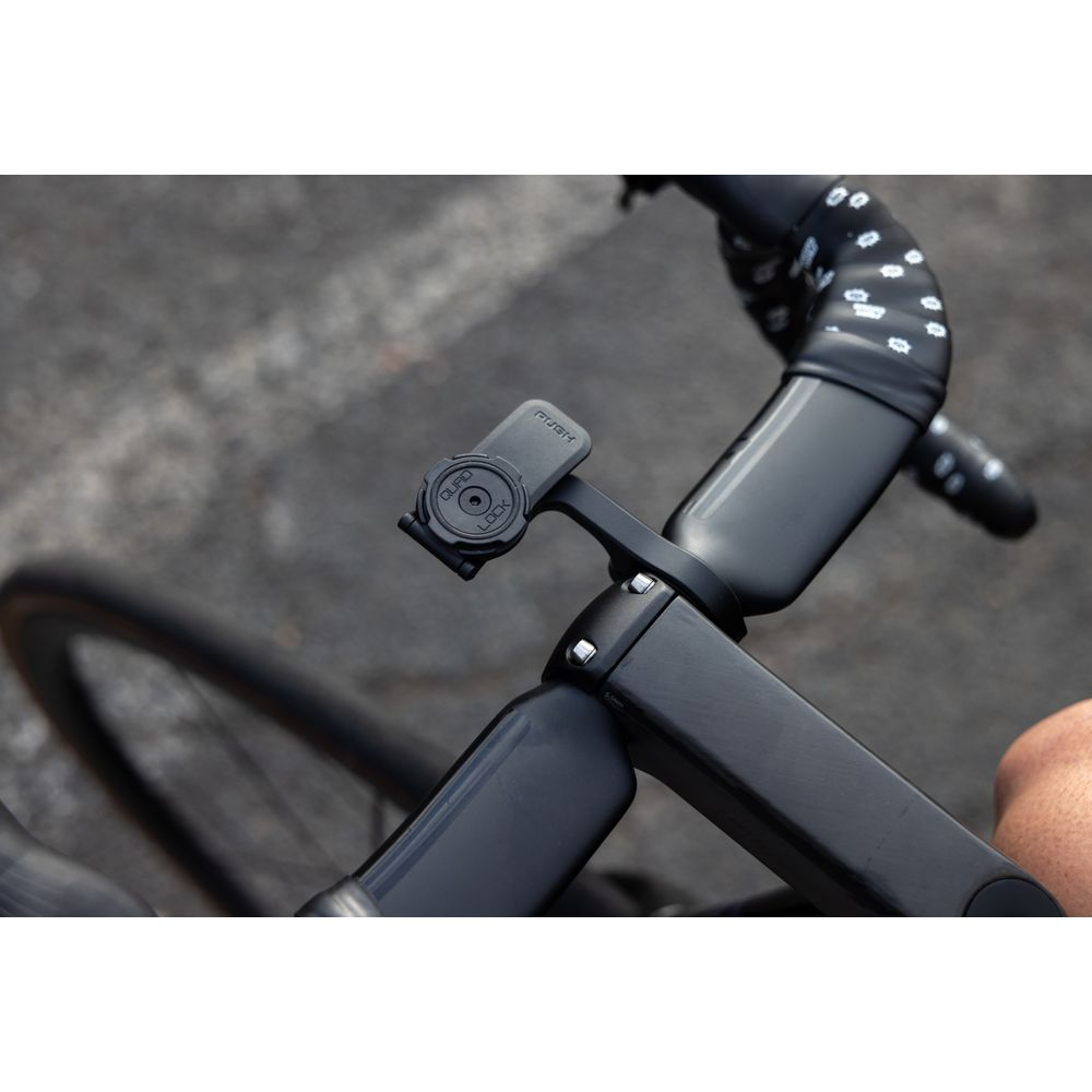 Schwarzer Fahrradlenker mit Quad Lock Halterung und Rad im Hintergrund.