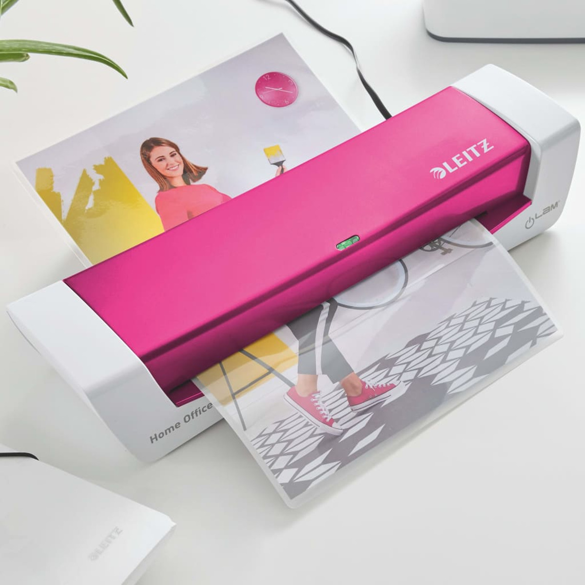 Ein pinker Laminator verarbeitet ein Bild mit roten Schuhen und einem Fahrrad.