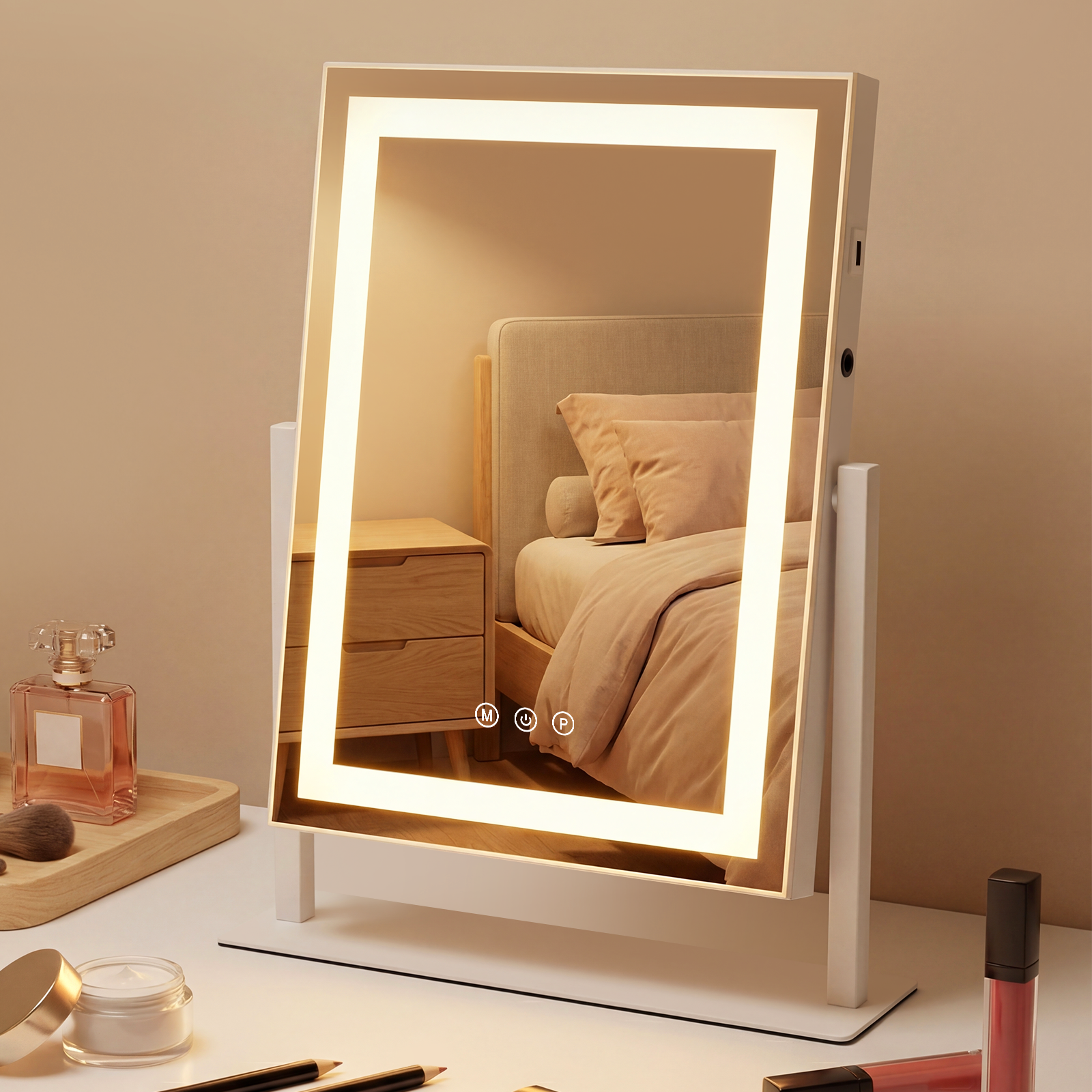 Un espejo de maquillaje iluminado refleja una cama con almohadas y una mesita de noche. Hay artículos de maquillaje sobre el escritorio.