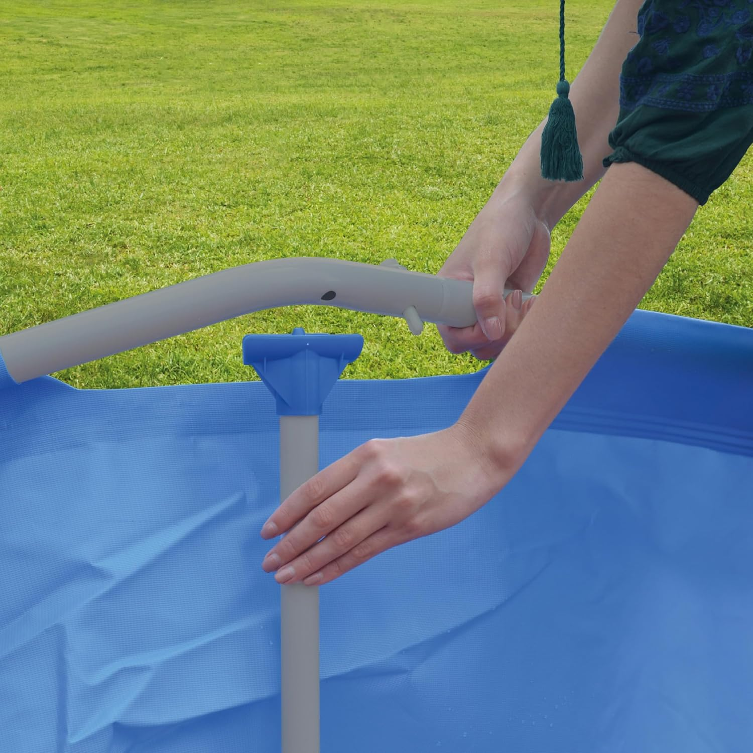Personen bauen einen blauen Pool im Freien auf, mit Gras im Hintergrund.