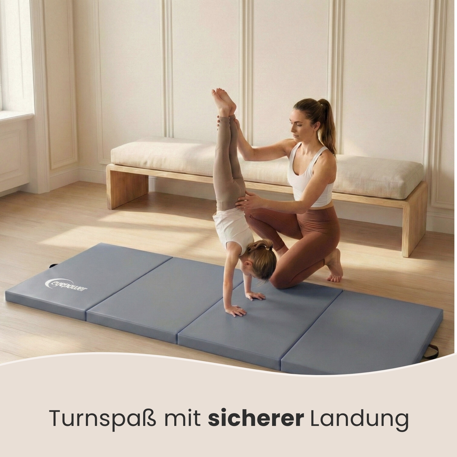 Eine Frau hilft einem Kind auf einer Gymnastikmatte beim Handstand.