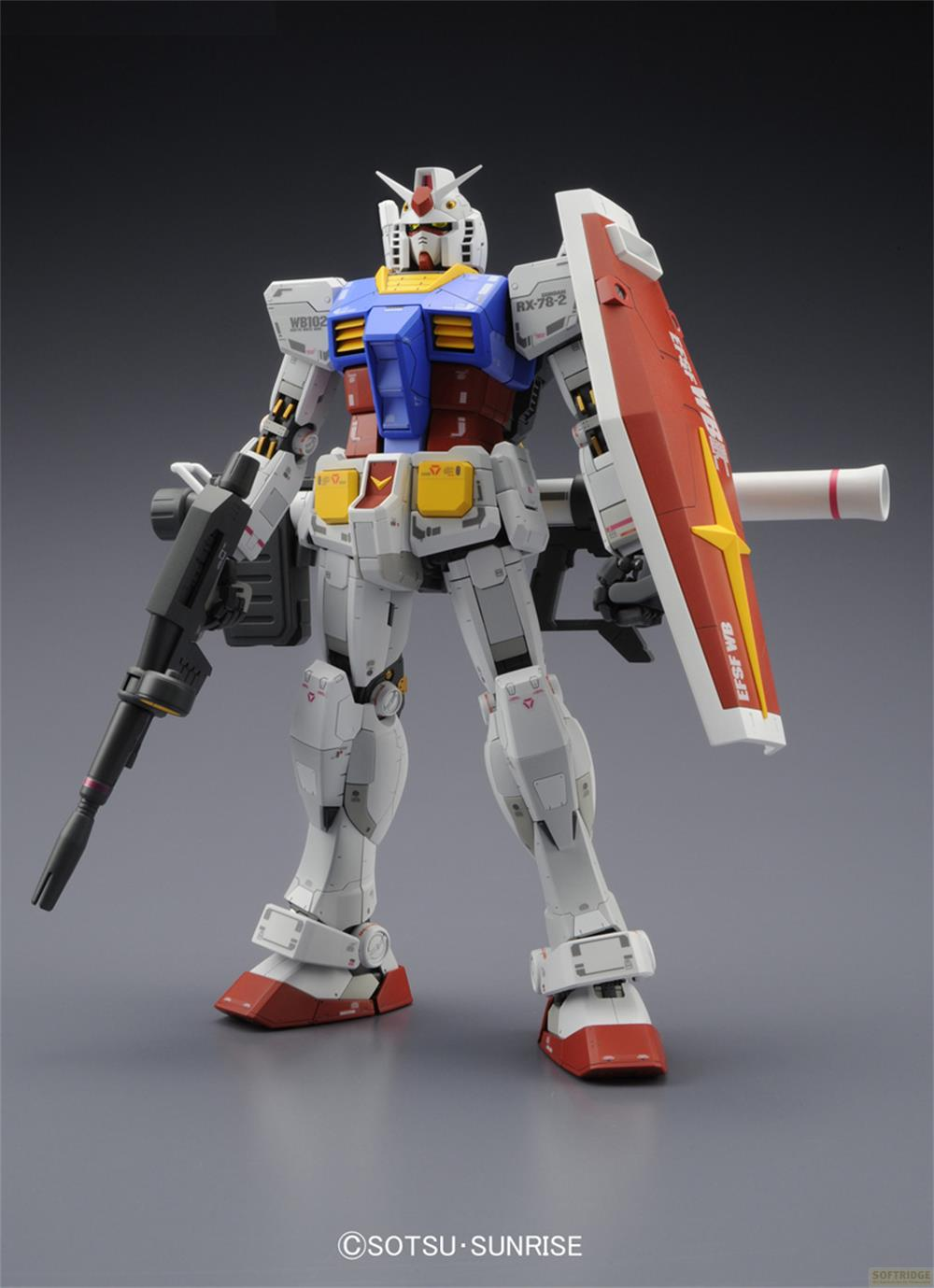 Ein weißer Gundam-Roboter mit blauer, roter und gelber Brust, hält eine Waffe und einen Schild.