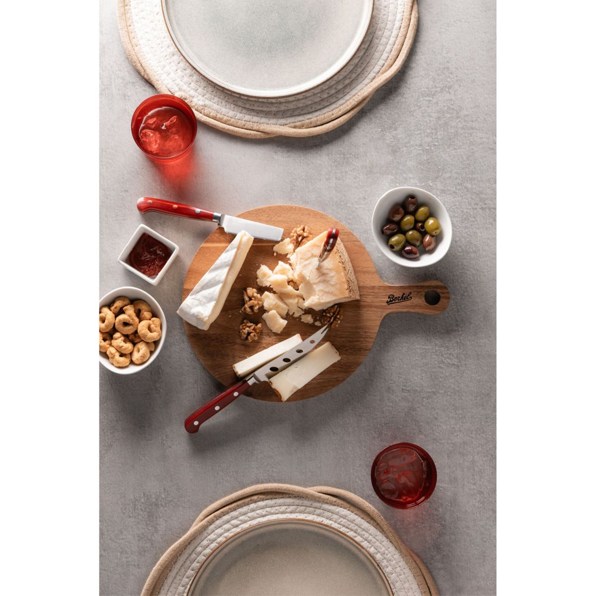 Käseplatte mit Brie, Parmesan, Oliven, Nüssen und Gebäck. Zwei Gläser Rotwein.