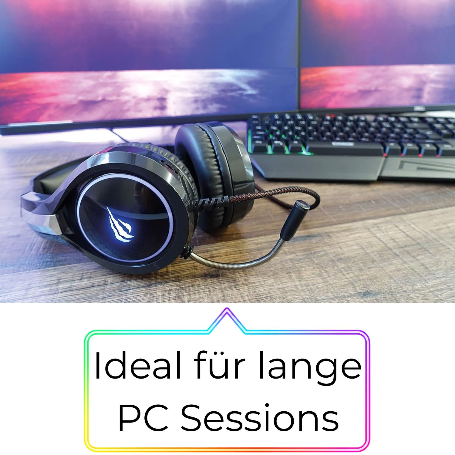 Schwarze Kopfhörer mit leuchtendem Logo auf einem Schreibtisch mit Tastatur und Monitoren.