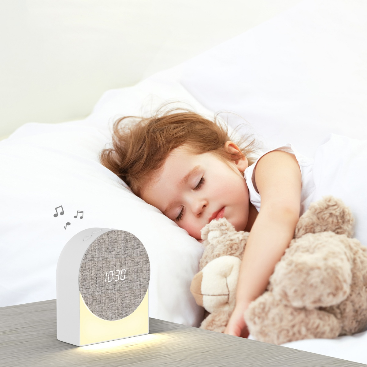Ein kleines Kind schläft friedlich mit einem Teddybären, ein Wecker steht daneben.