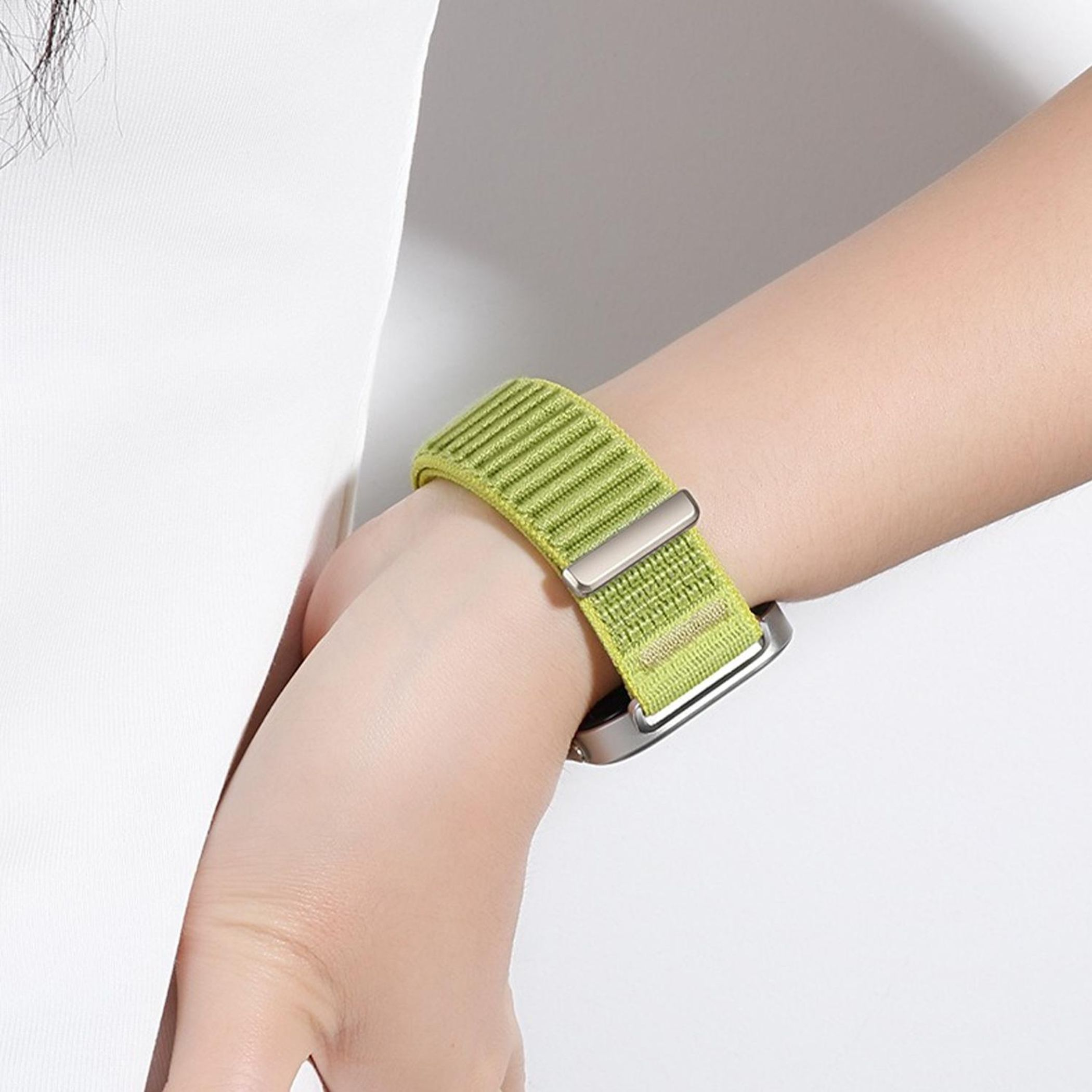 Eine Person trägt ein grünes gewebtes Uhrenarmband mit einer Silberschnalle.