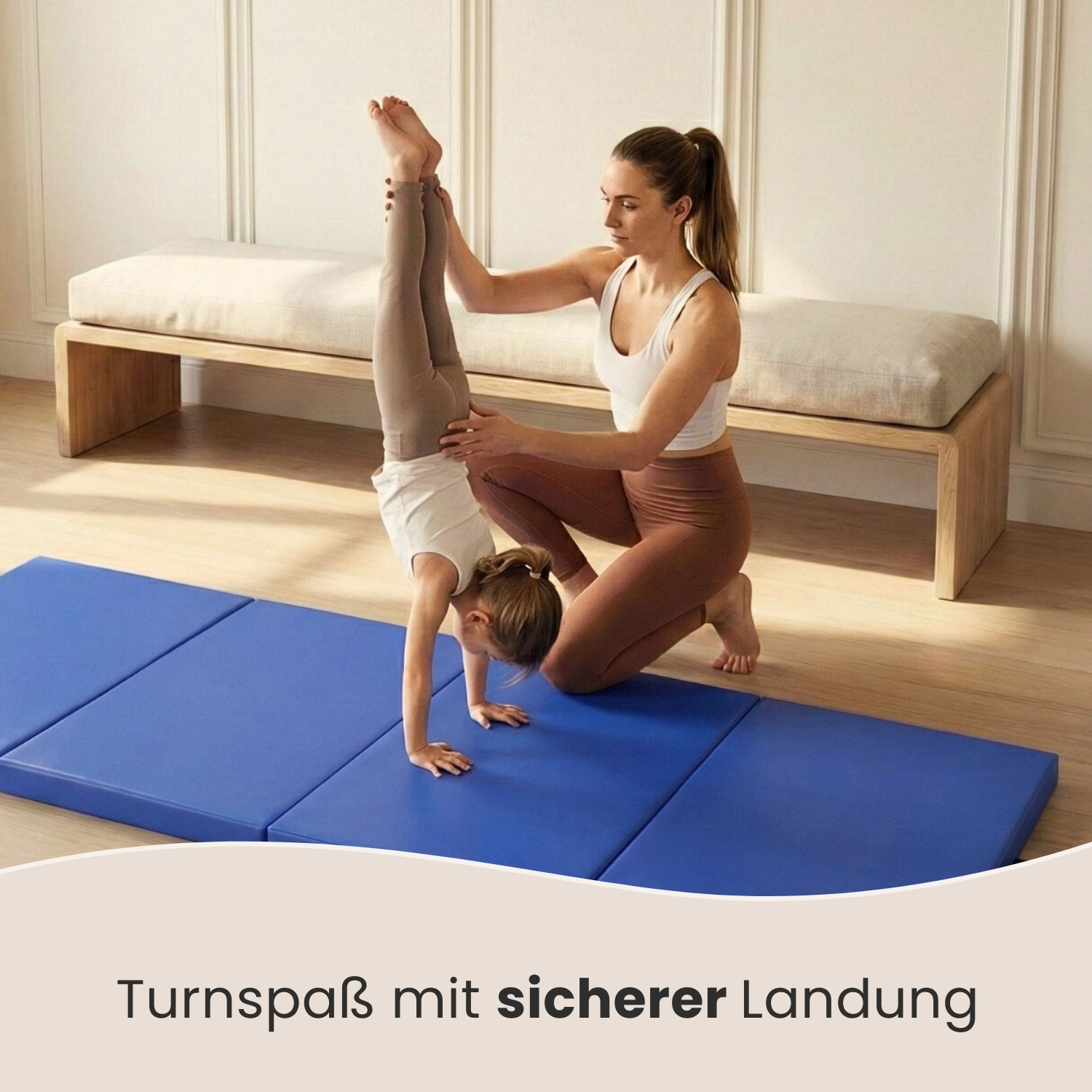 Eine Frau hilft einem Mädchen bei einem Handstand auf blauen Turnmatten.