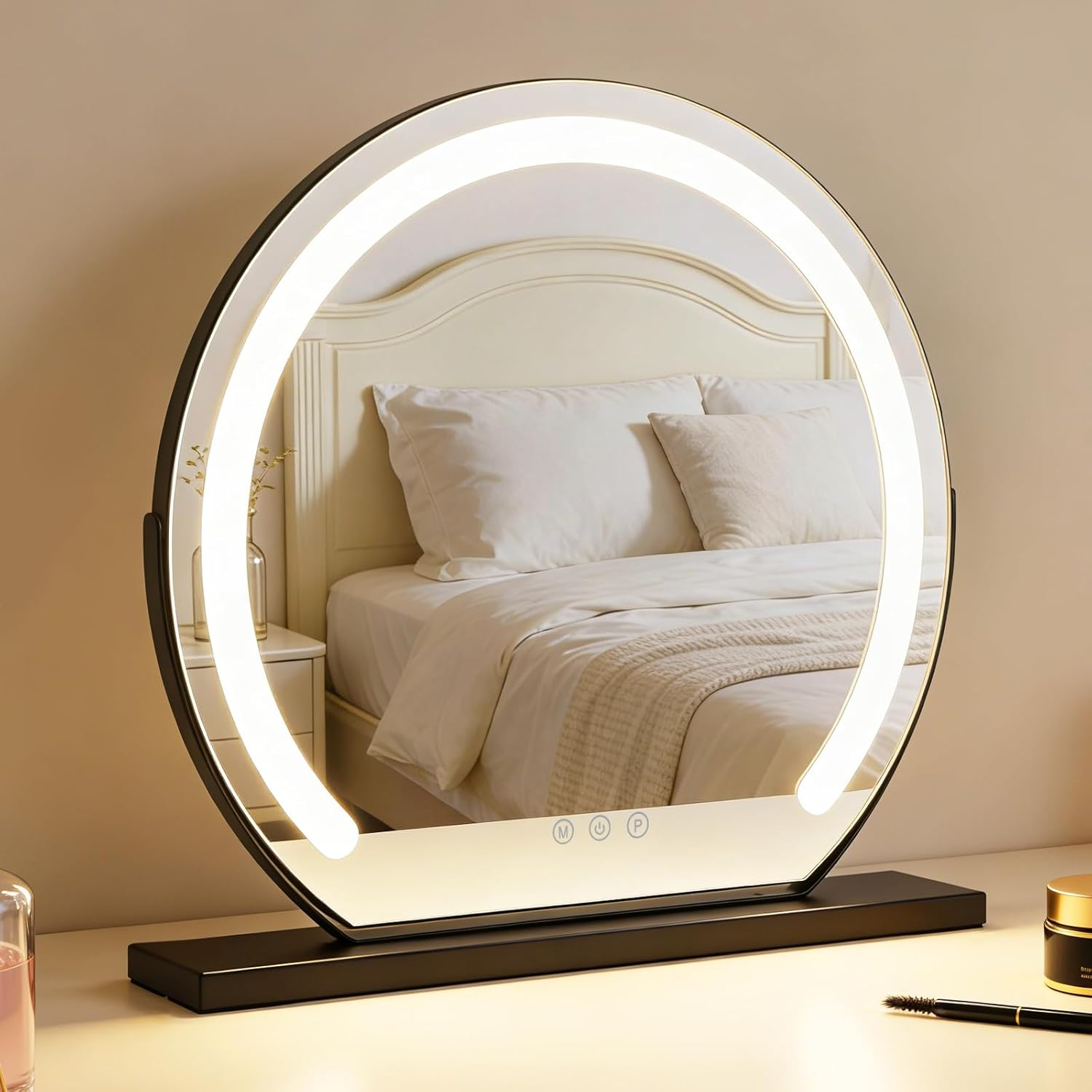 Uno specchio da trucco rotondo illuminato è su un tavolo. Un letto è riflesso nello specchio.