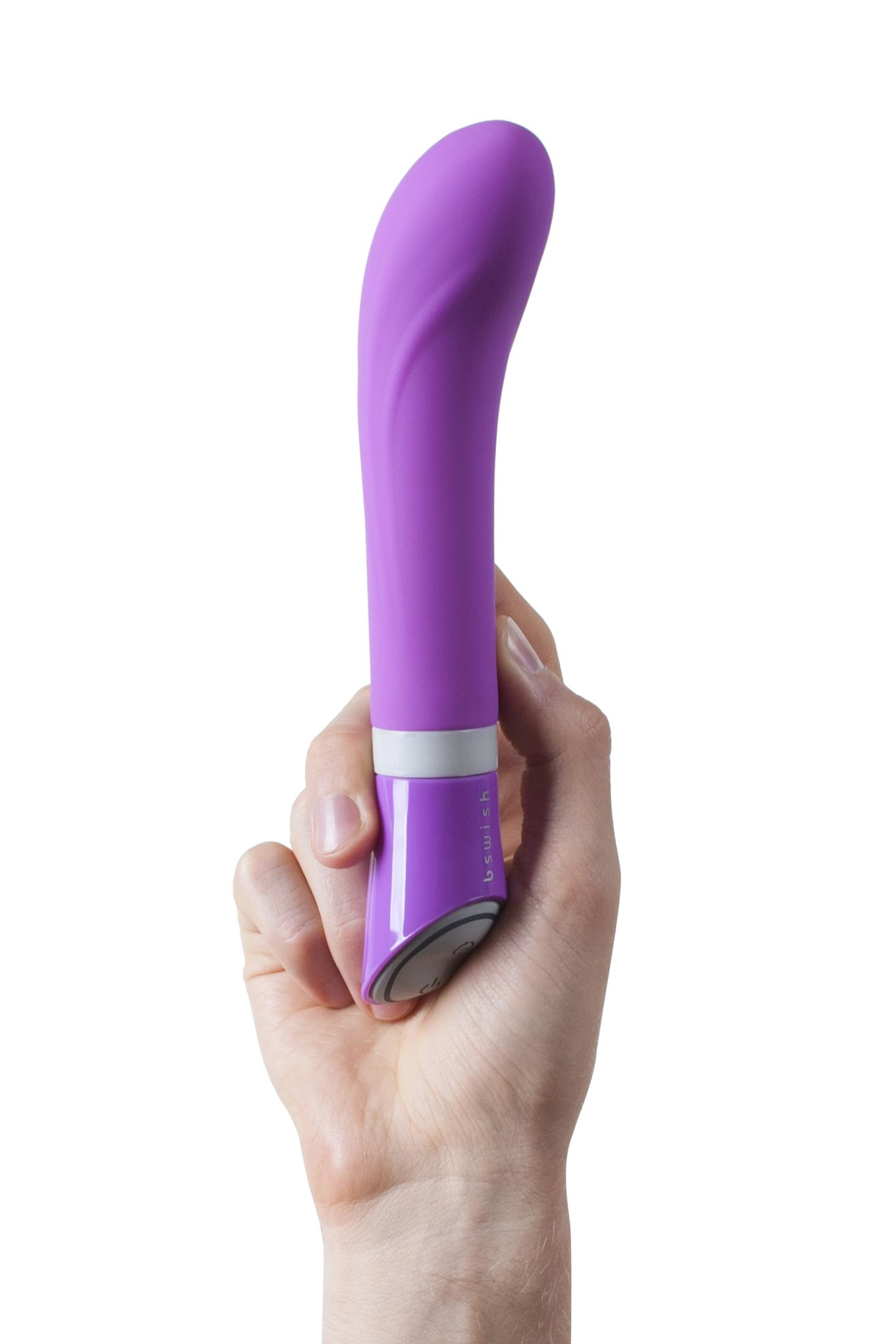 Eine Hand hält einen lila Vibrator mit einem grauen Ring und silbernem Knopf.