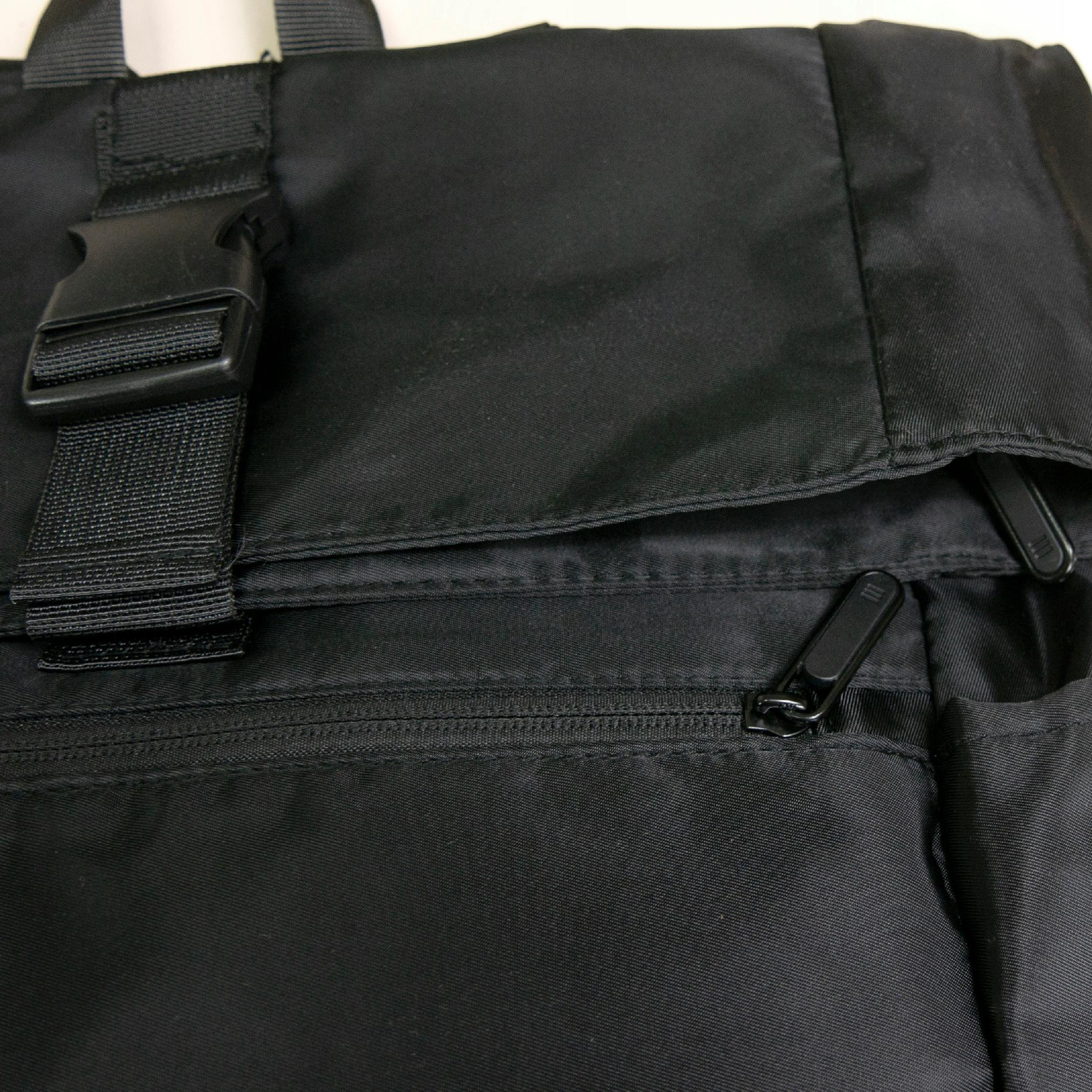Primo piano di una borsa in tessuto nero con zip e fibbie.
