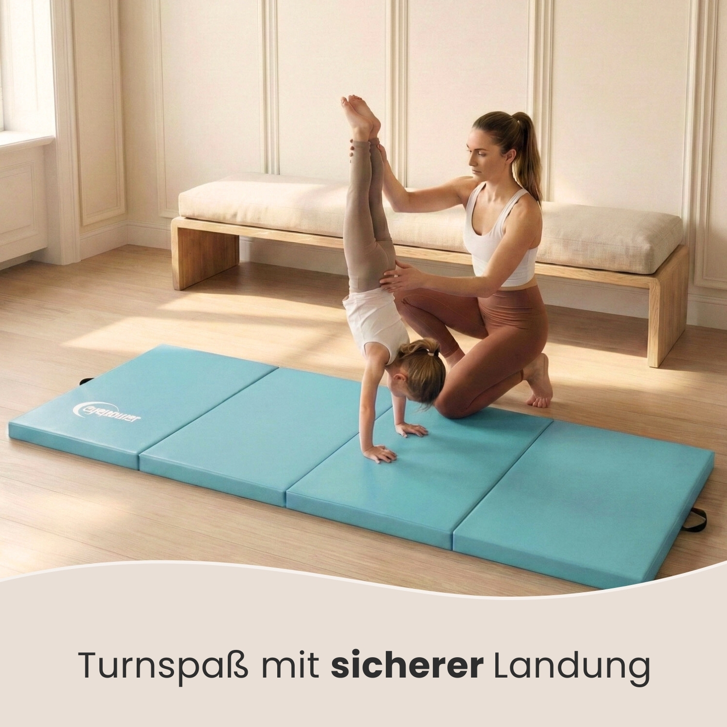 Frau hilft Kind bei Handstand auf blauer Matte. Helle, luftige Turnhalle.