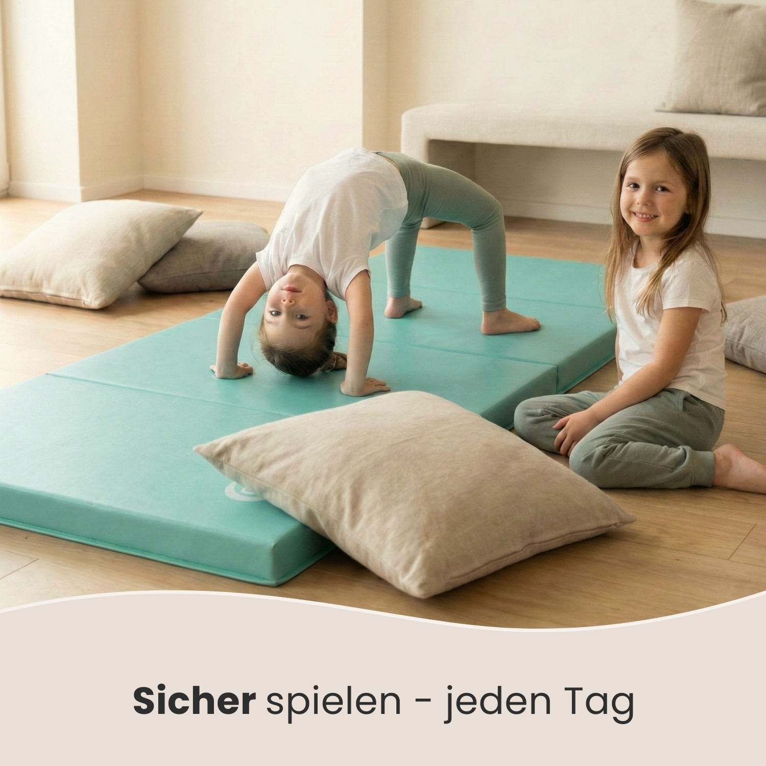 Zwei Mädchen üben auf einer Matte Akrobatik, eines in einer Brücke, das andere sitzt lächelnd.