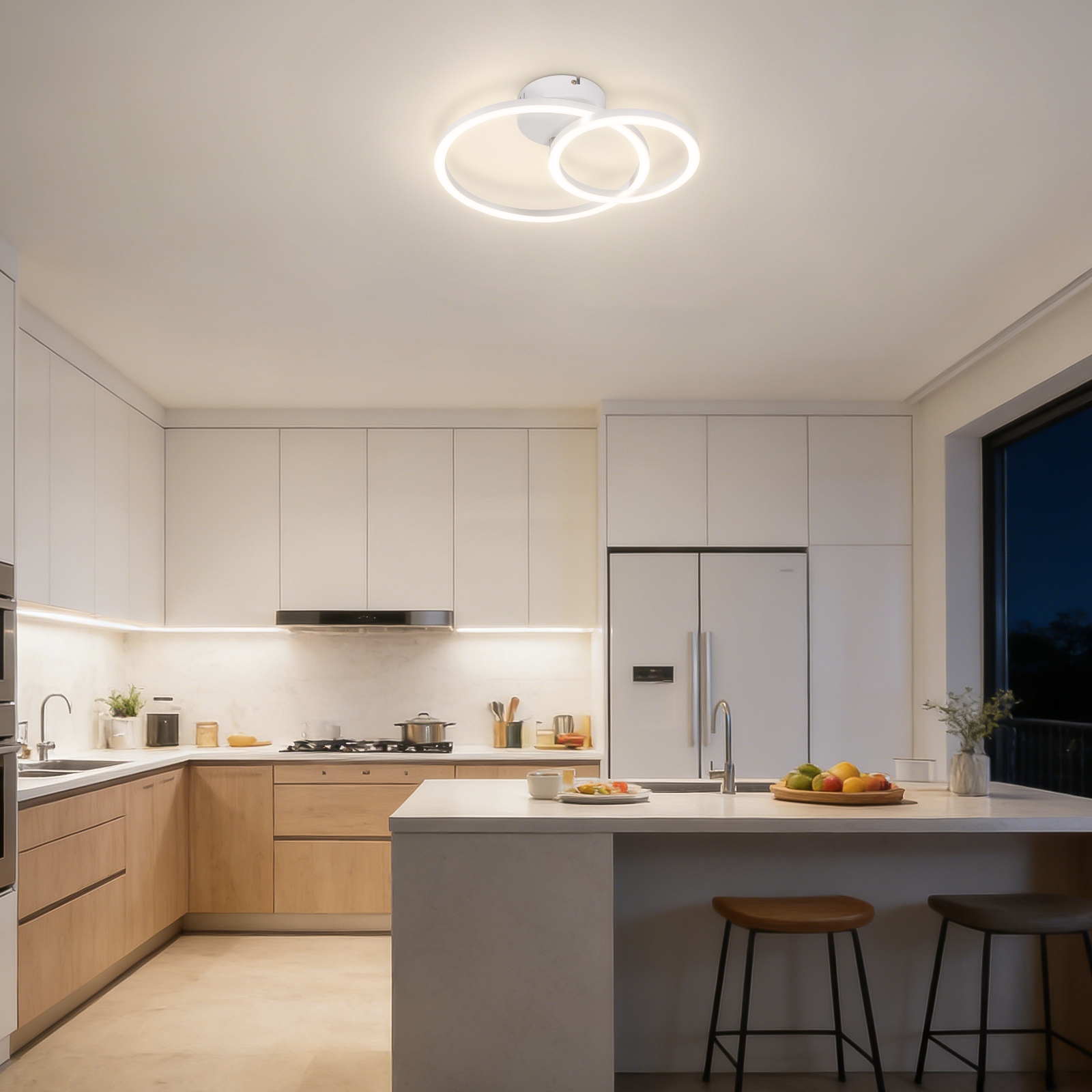 Cucina moderna con isola, frigorifero, fornelli, lavello e lampada a sospensione.