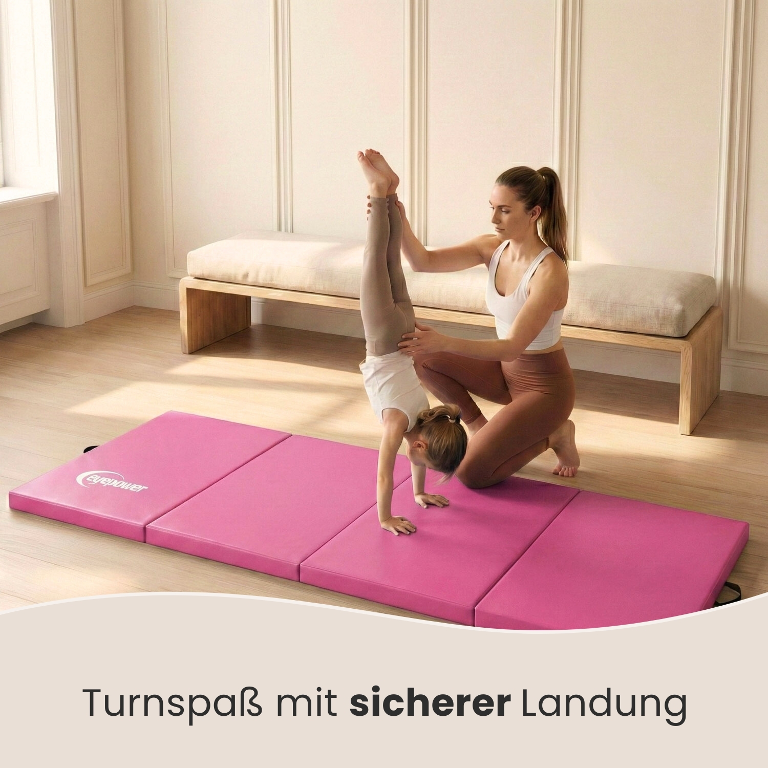 Eine Frau hilft einem Kind bei einem Handstand auf einer rosa Matte.