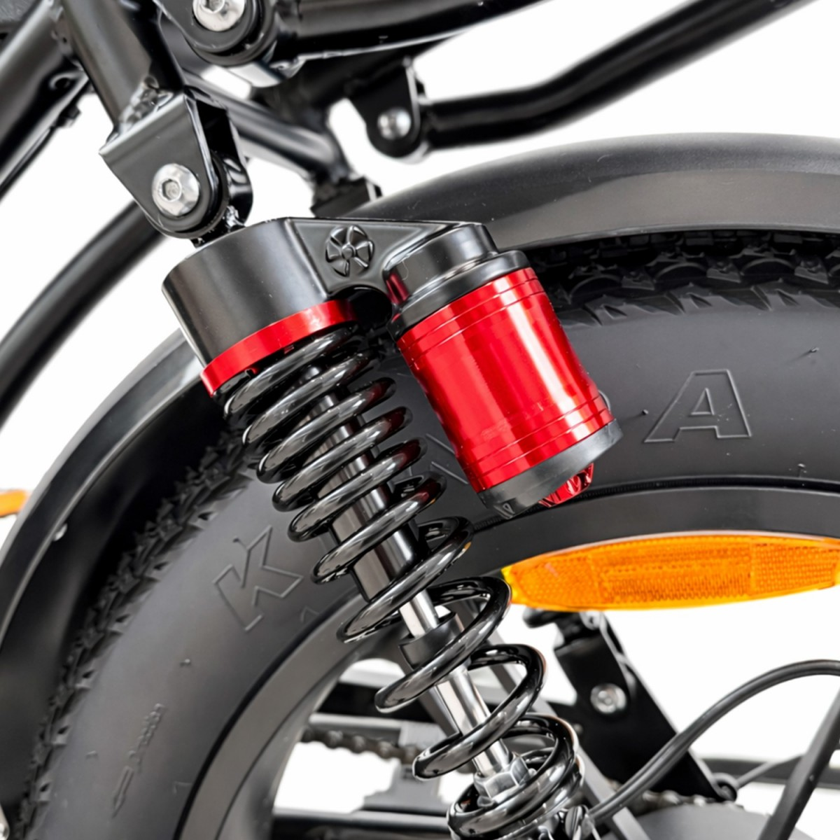 Zbliżenie amortyzatora rowerowego z czerwonym zbiorniczkiem i czarną sprężyną.