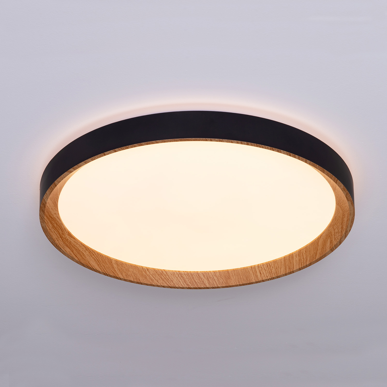 Luz de techo redonda con marco de madera y negro, iluminada.