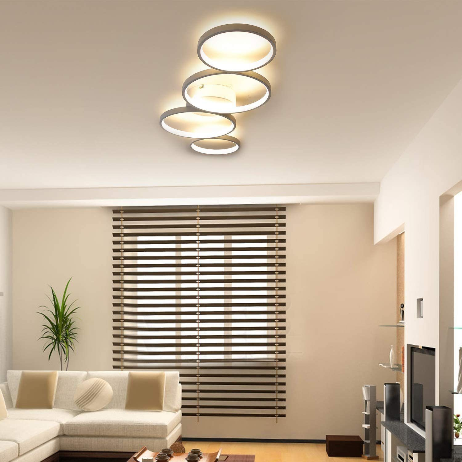 Nowoczesny salon z sofą narożną, żaluzjami i abstrakcyjną lampą sufitową.