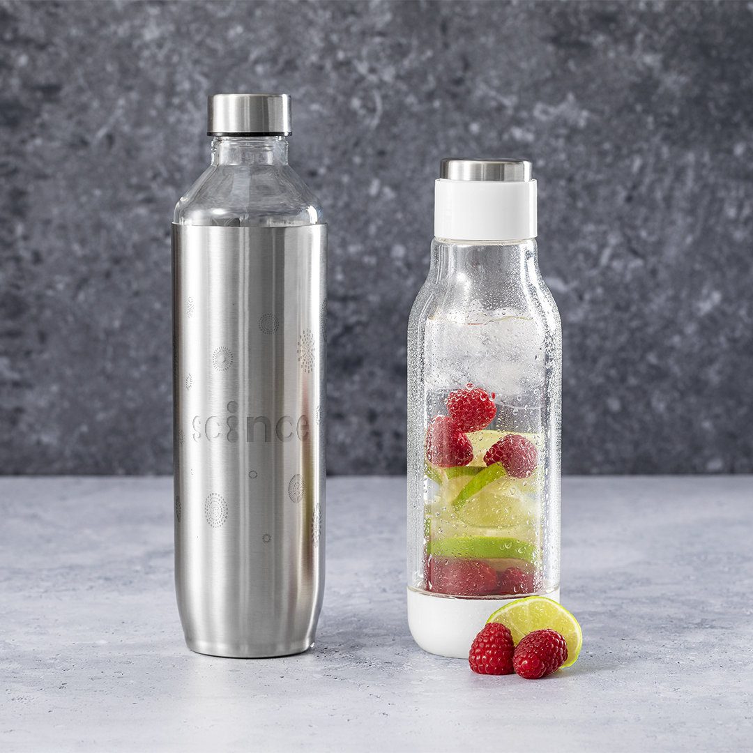Dos botellas sobre una mesa: una de acero inoxidable con patrón, una de cristal con bayas y rodajas de lima.