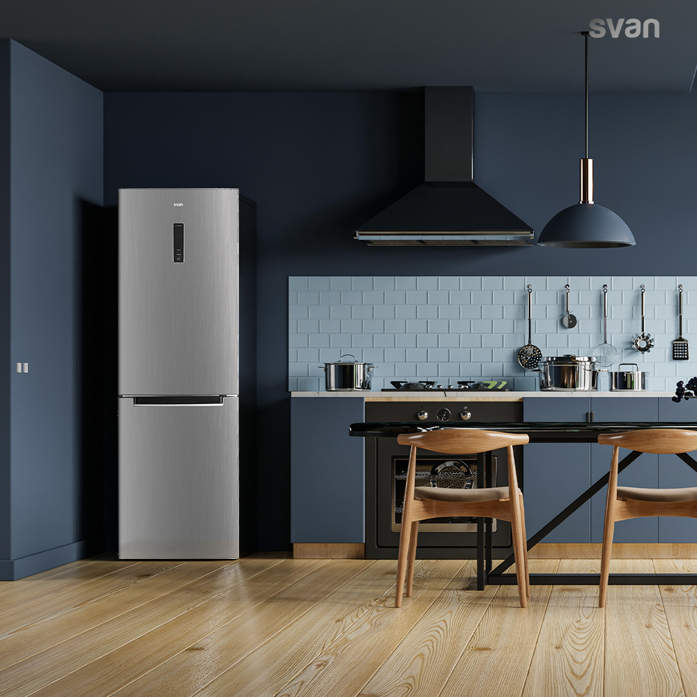Cocina moderna con frigorífico plateado, paredes azules, salpicadero de azulejos metro y suelo de madera.