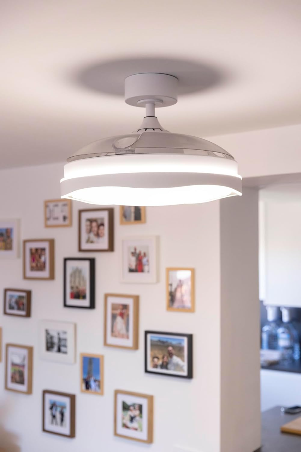 Ventilador de techo con luz sobre una pared llena de fotos enmarcadas.