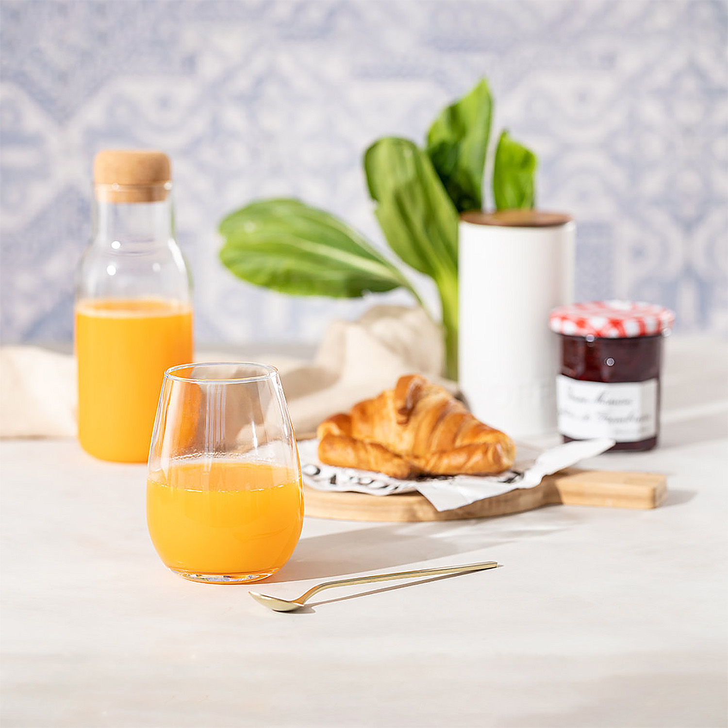 Un bicchiere di succo d'arancia, un croissant e marmellata su un tavolo.