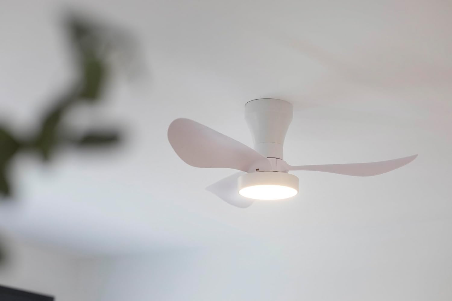 Un ventilador de techo blanco con luz está montado en un techo blanco.