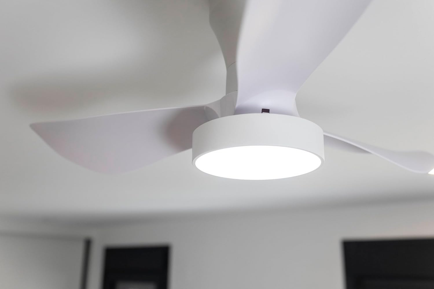 Un ventilador de techo blanco moderno con luz integrada sobre fondo blanco.