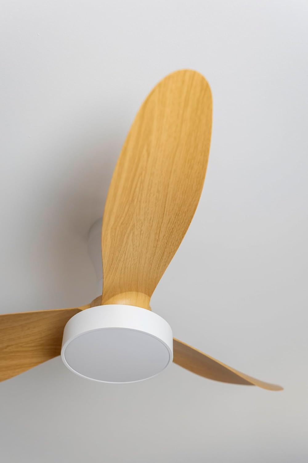 Un ventilador de techo moderno con tres aspas de madera y un centro blanco.