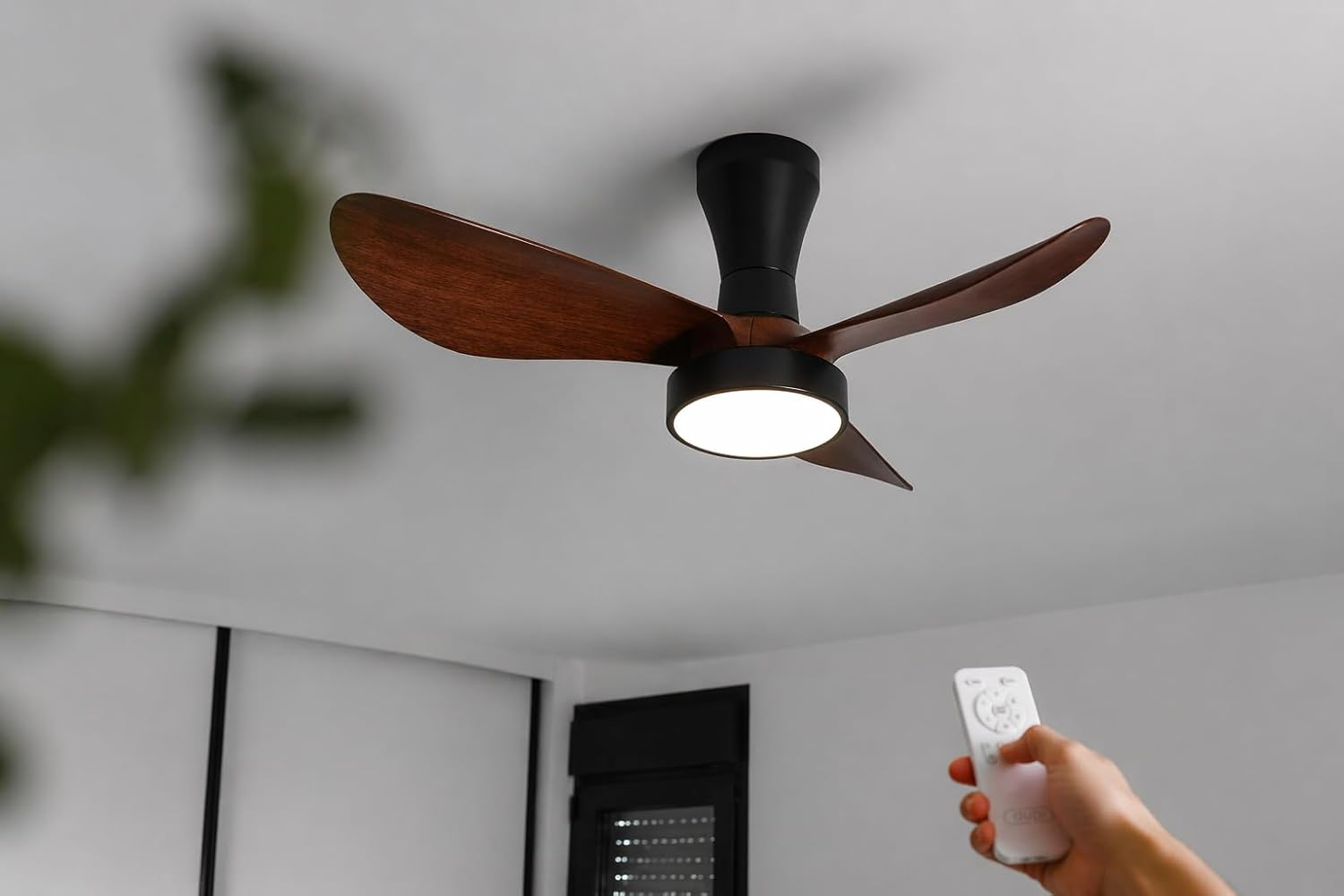 Un ventilador de techo con aspas de madera y luz es controlado por un mando.