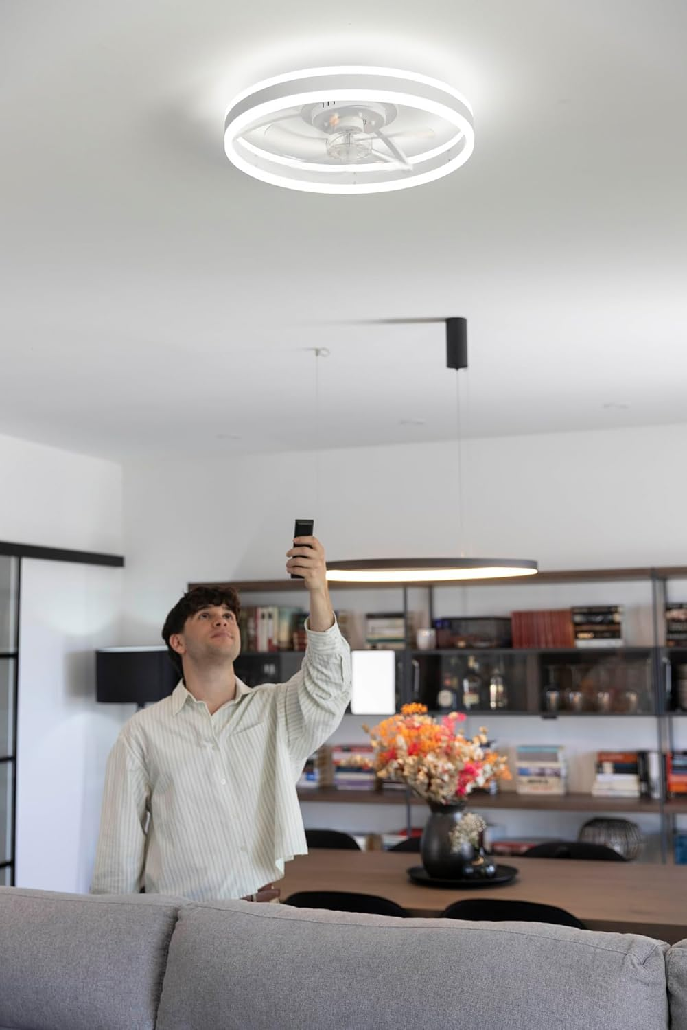 Un hombre sostiene un control remoto mirando una luz de techo.