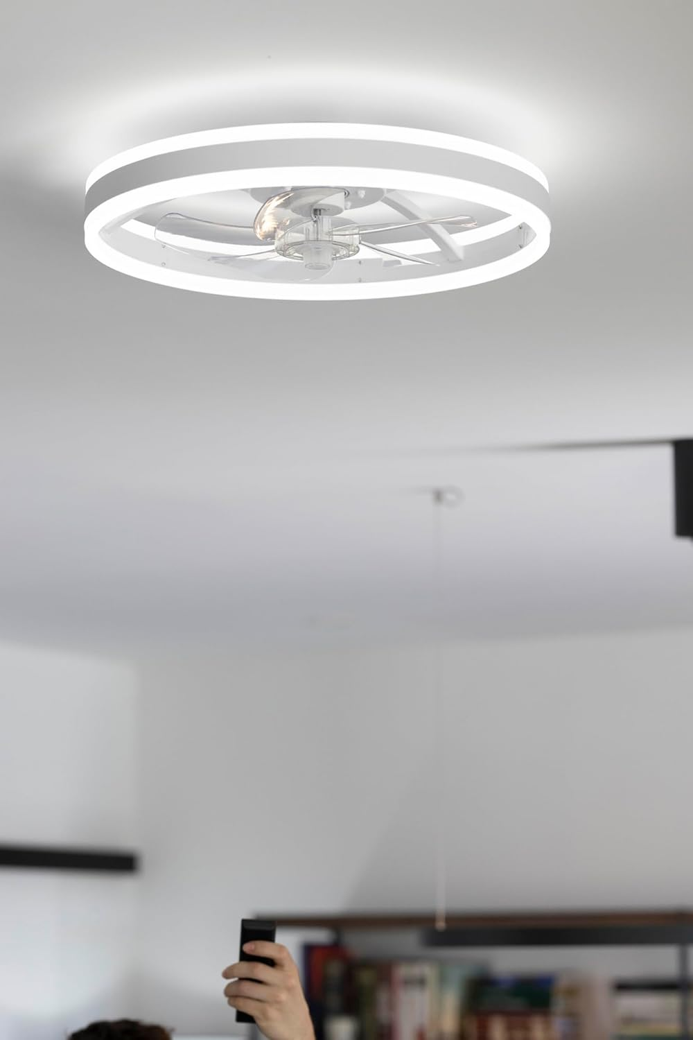 Un ventilador de techo moderno con luz de anillo LED cuelga del techo.