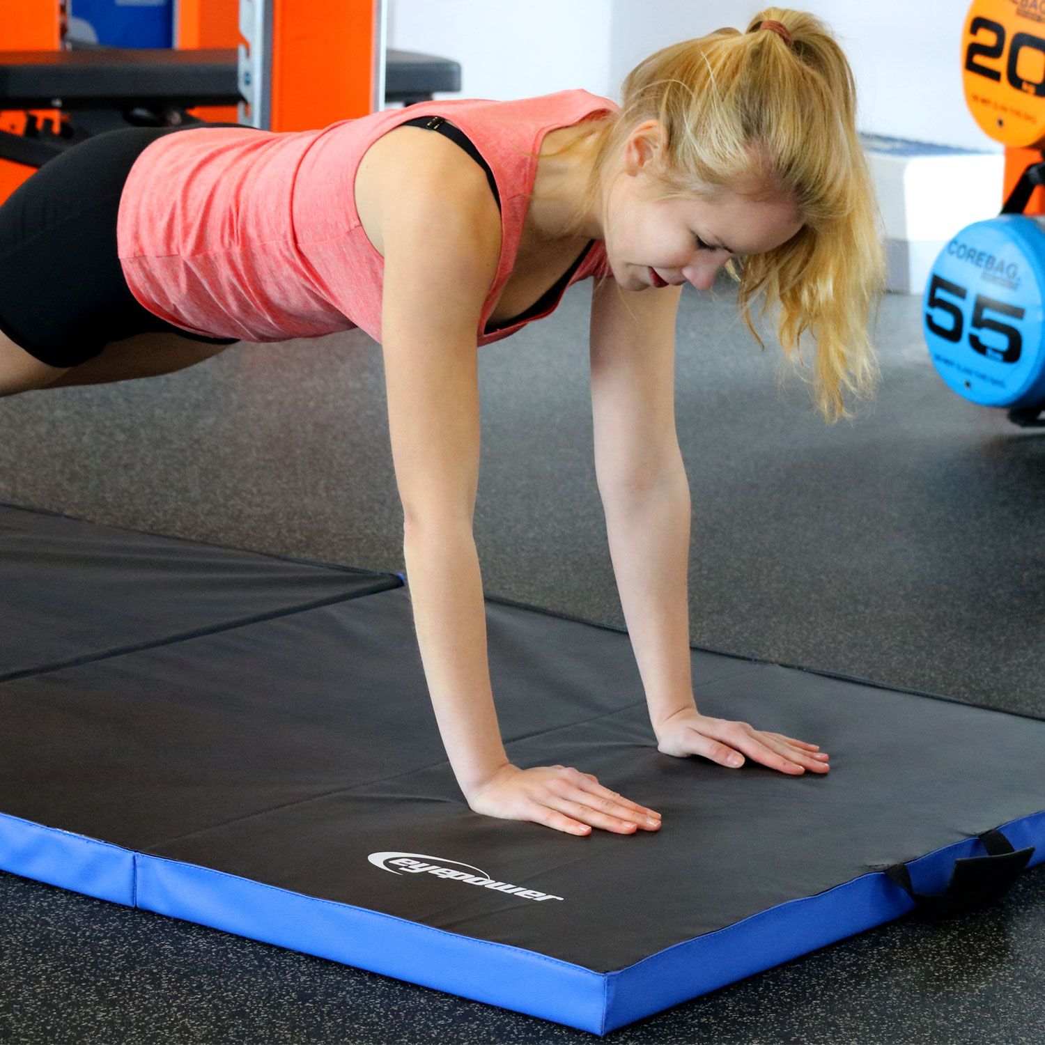 Eine Frau macht einen Unterarmstütz auf einer Matte in einem Fitnessstudio.