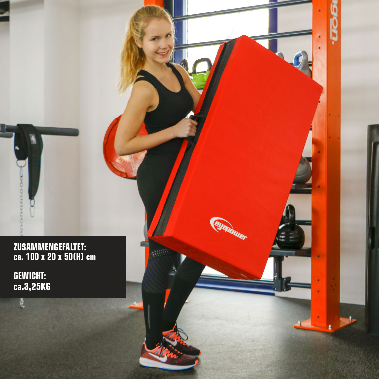 Frau im Fitnessstudio hält ein großes, rotes Kissen mit schwarzem Rand.
