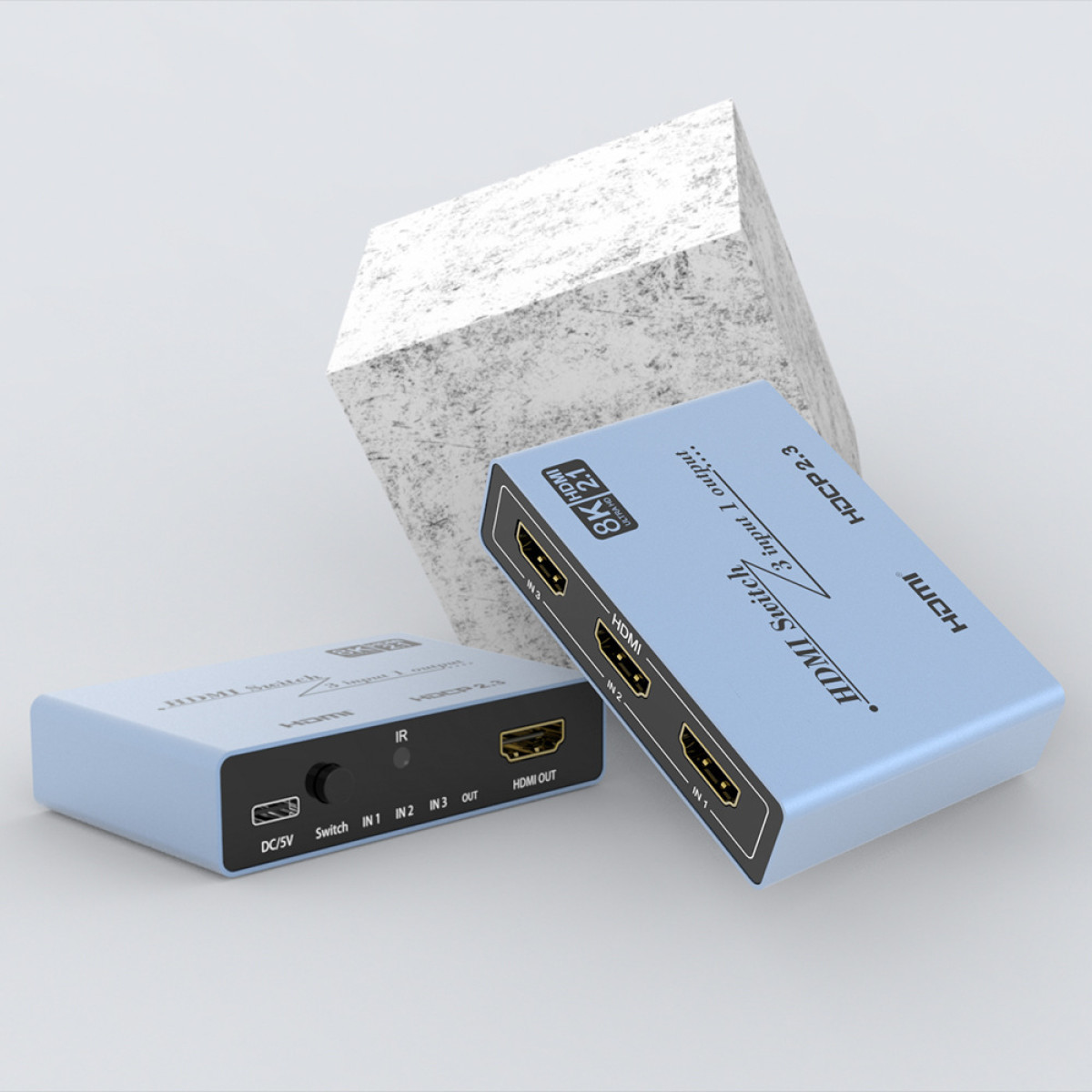 Zwei hellblaue HDMI-Umschalter mit 3 Eingängen und 1 Ausgang stehen neben einem Stein.