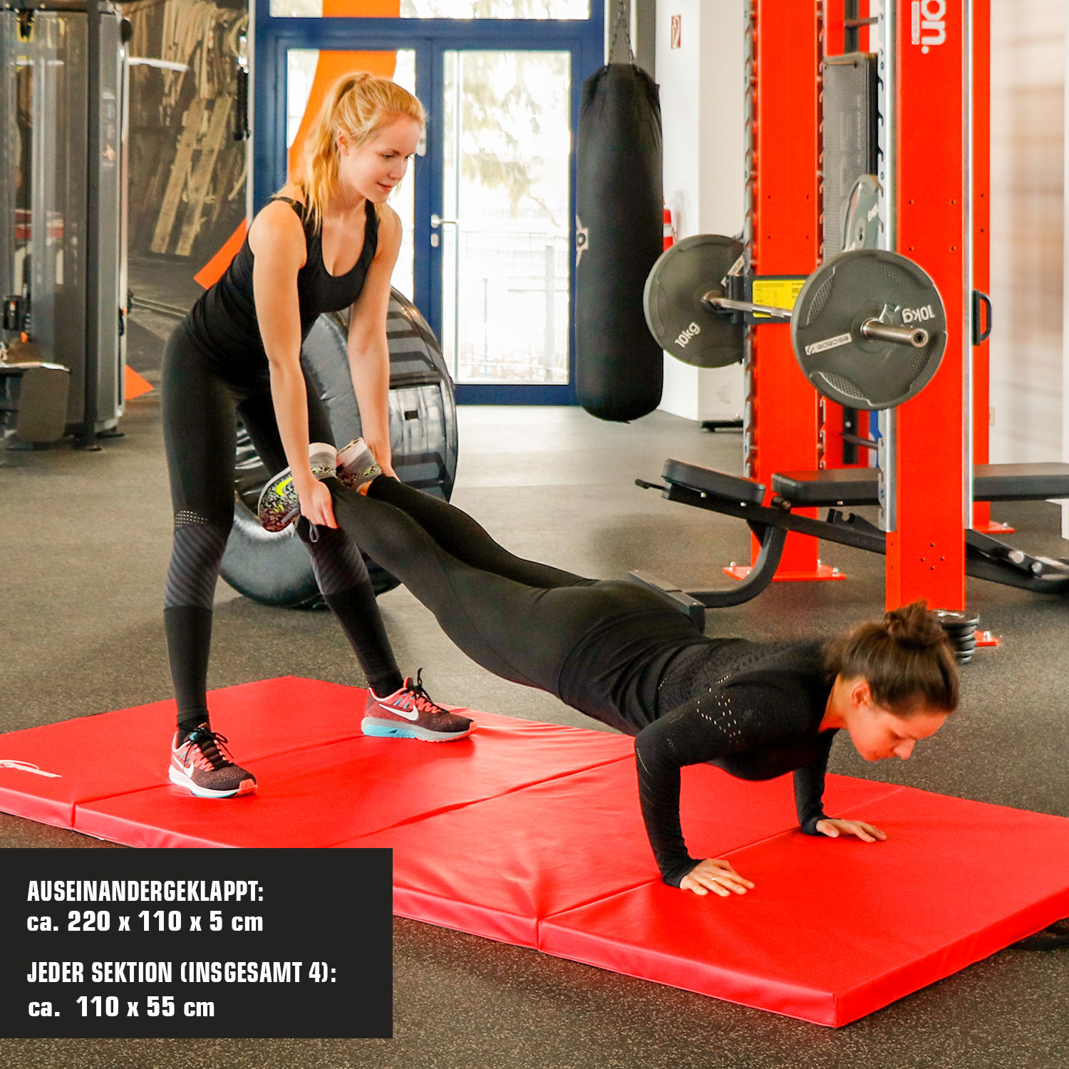 Zwei Frauen trainieren im Fitnessstudio; eine macht Liegestütze, die andere hilft.