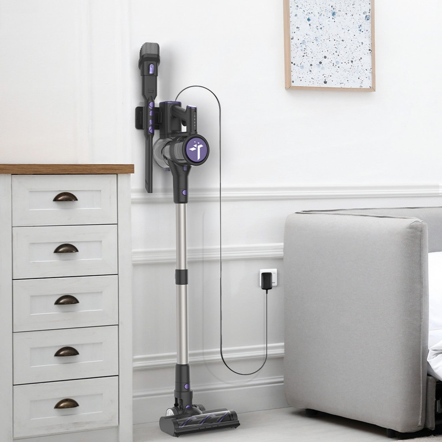 Un aspirador inalámbrico está en un soporte de pared junto a una cómoda blanca.
