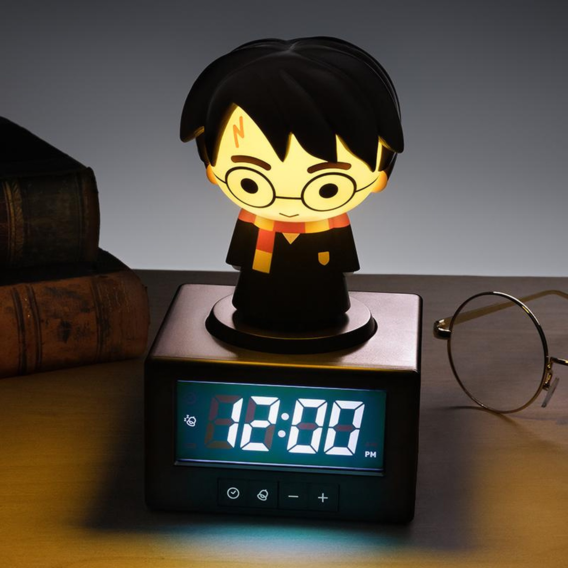 Świecąca figurka Harry'ego Pottera siedzi na czarnym cyfrowym budziku pokazującym 12:00.