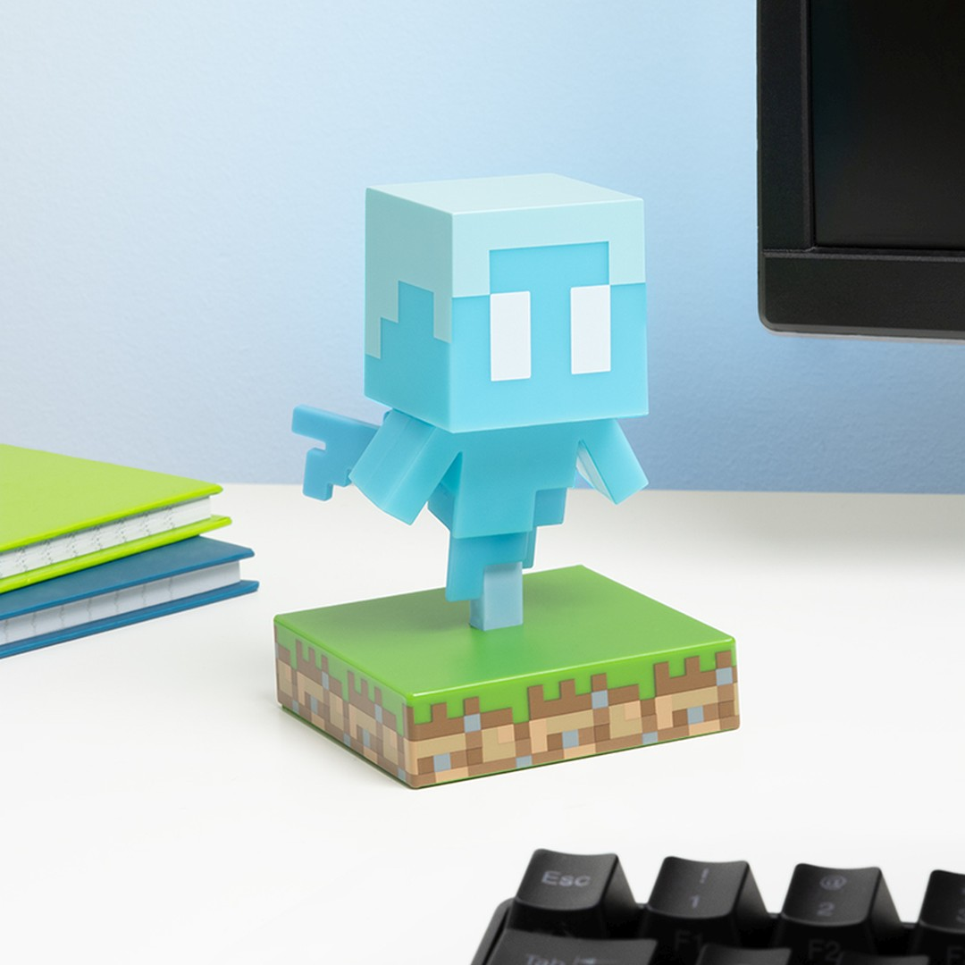 Niebieska figurka Minecraft Allay na podstawie bloku trawy. W pobliżu książki i klawiatura.