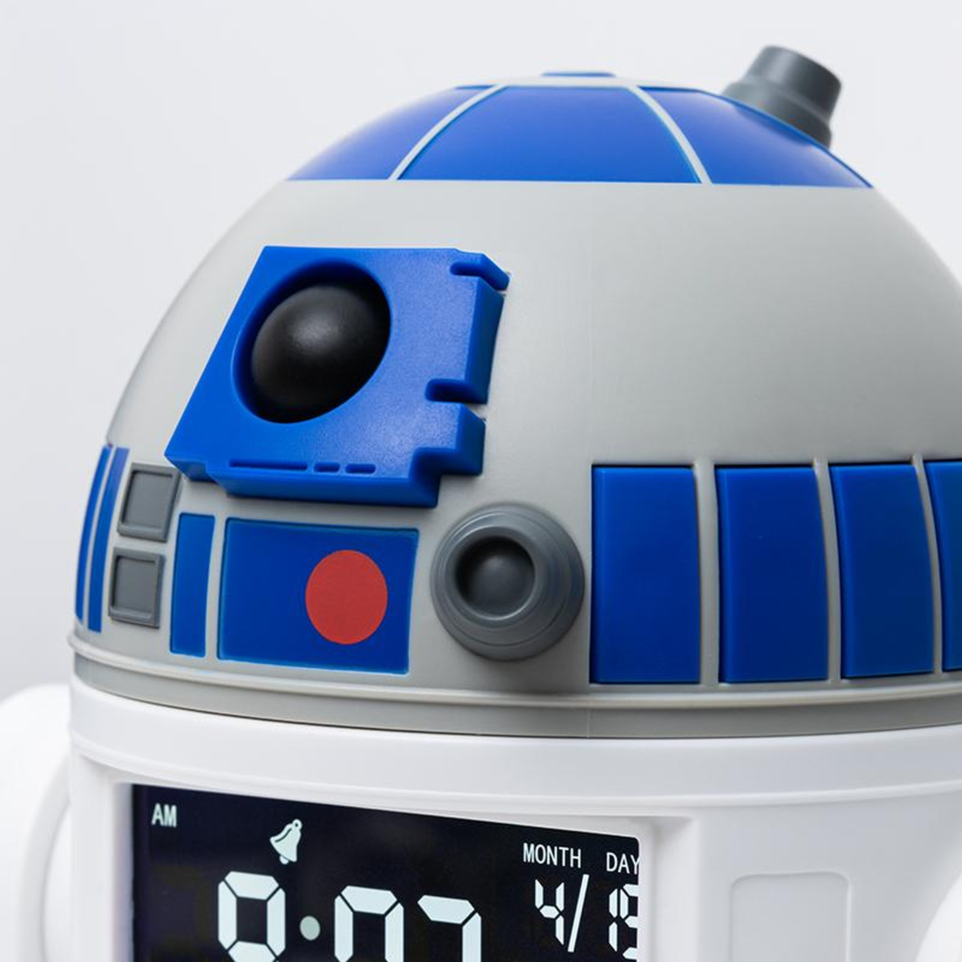 Zbliżenie na budzik R2-D2. Widoczne niebieskie, białe i szare detale. Wyświetlacz cyfrowy pokazuje czas.
