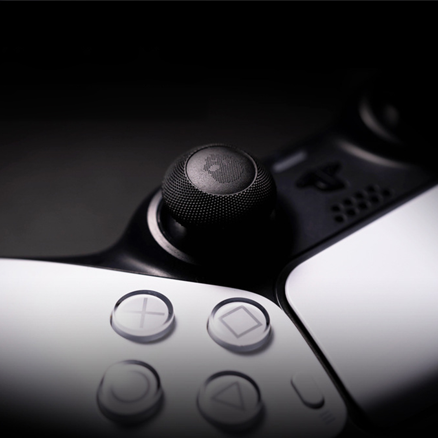 Close-up van een zwarte controller met zilveren knoppen en een gestileerd schedel-embleem.