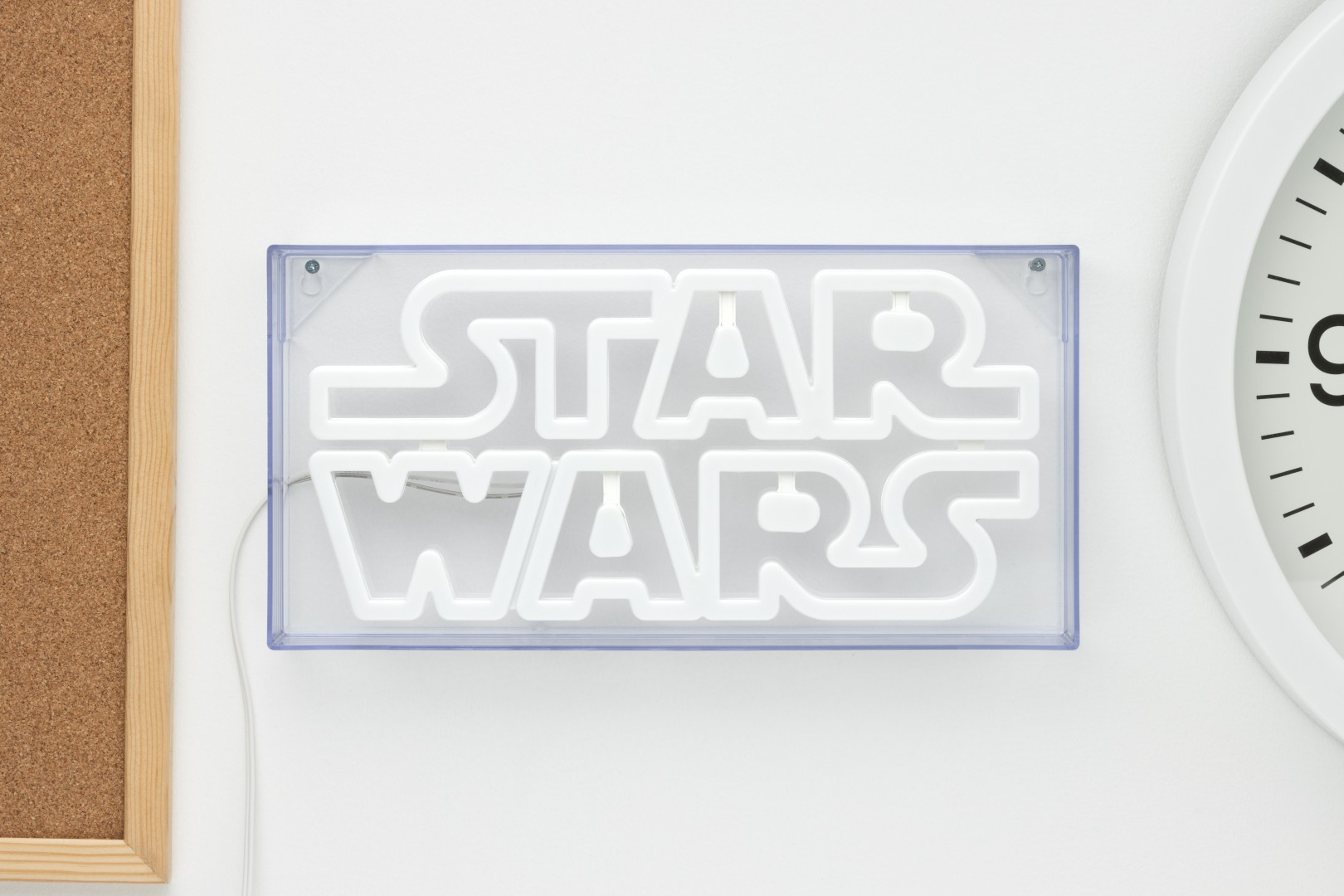 Biały neonowy napis "STAR WARS" jest zamontowany na ścianie obok zegara.