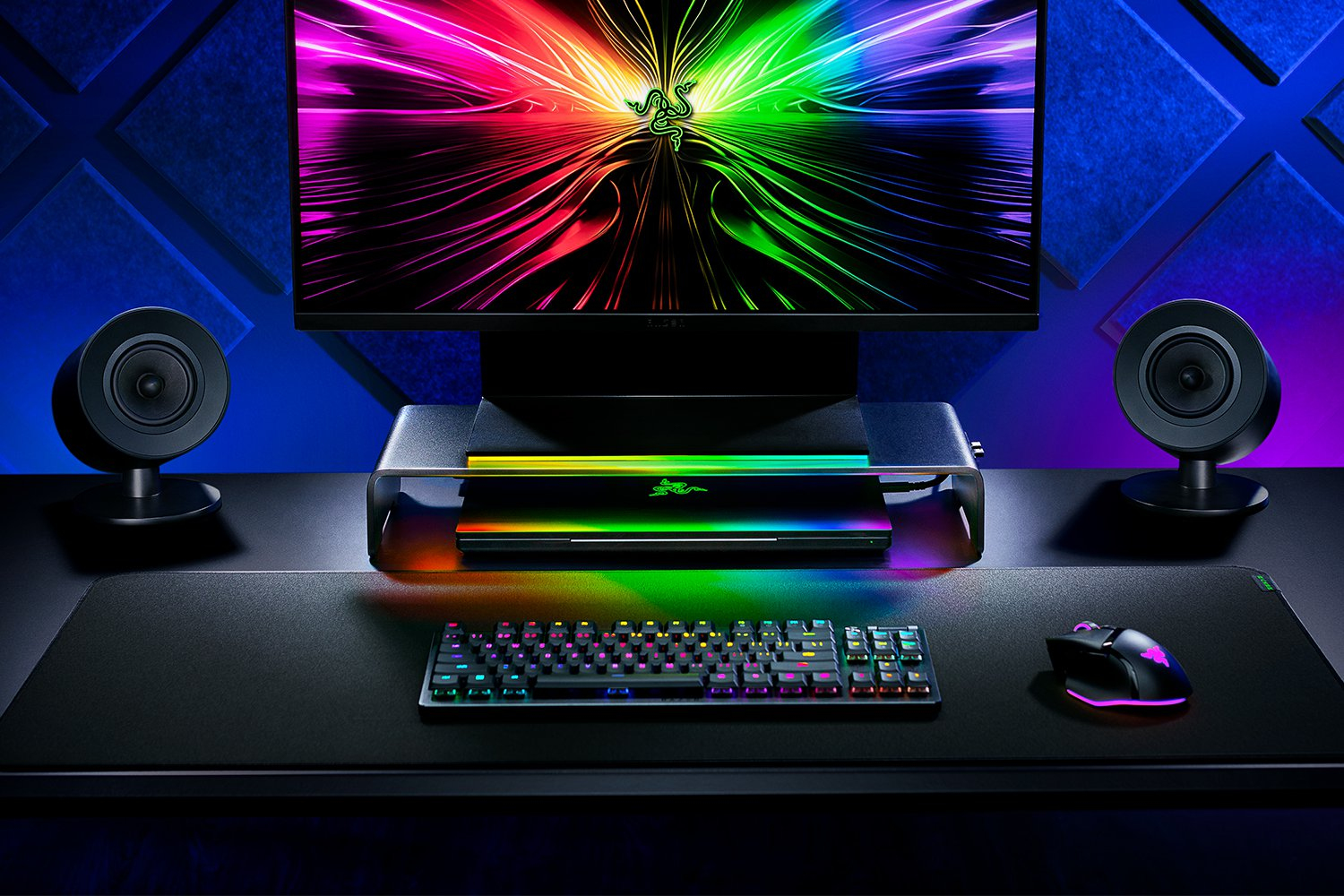 Gaming-Setup mit beleuchteter Tastatur, Maus, Lautsprechern und Laptop.