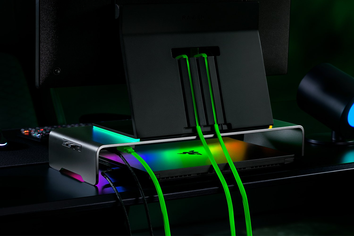 Ein schwarzer Razer Laptopständer mit RGB-Beleuchtung, der einen Laptop und Kabel hält.