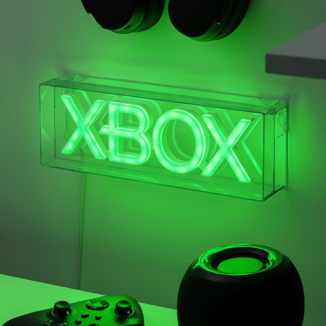Zielony neonowy znak XBOX w przezroczystym pudełku, z kontrolerem w pobliżu.